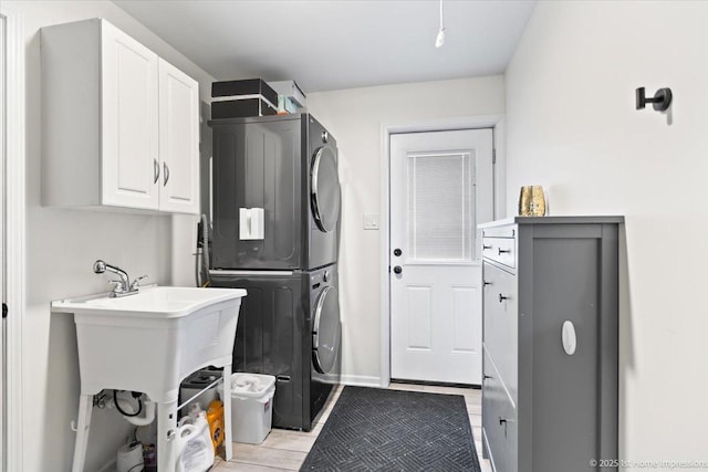 laundry area with cabinets and stacked washer / dryer