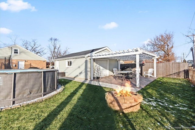 rear view of property featuring a fire pit, a yard, a pergola, and a patio