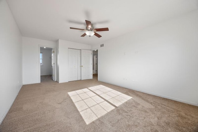 unfurnished bedroom with ceiling fan, light colored carpet, and a closet