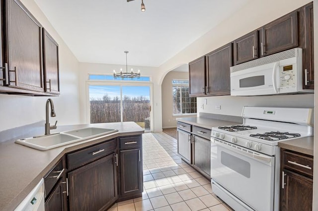 kitchen with dark brown cabinetry, sink, white appliances, and decorative light fixtures