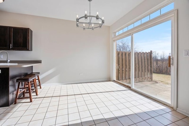 tiled dining room with sink and a chandelier