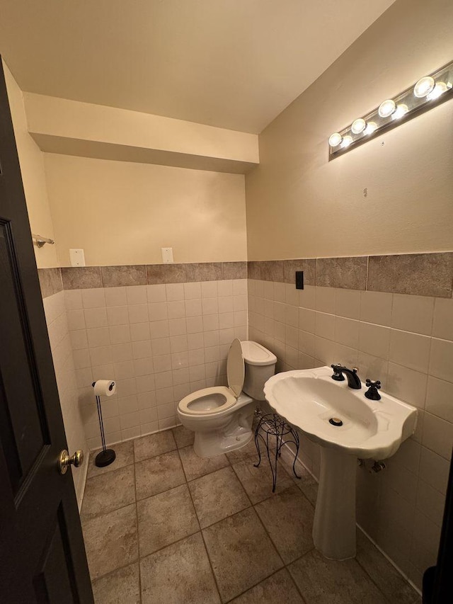 bathroom featuring sink, tile walls, and toilet