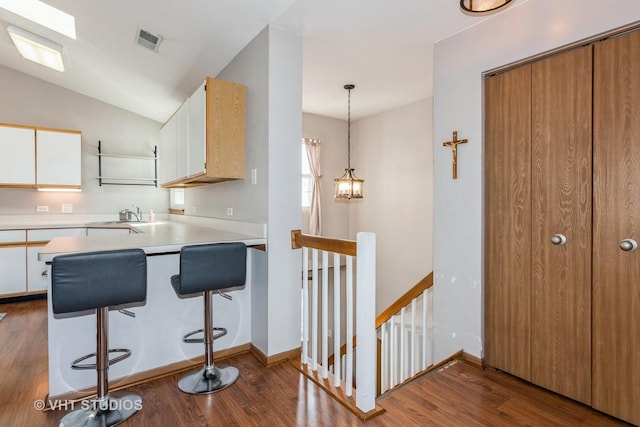 kitchen with white cabinetry, hanging light fixtures, hardwood / wood-style flooring, and sink