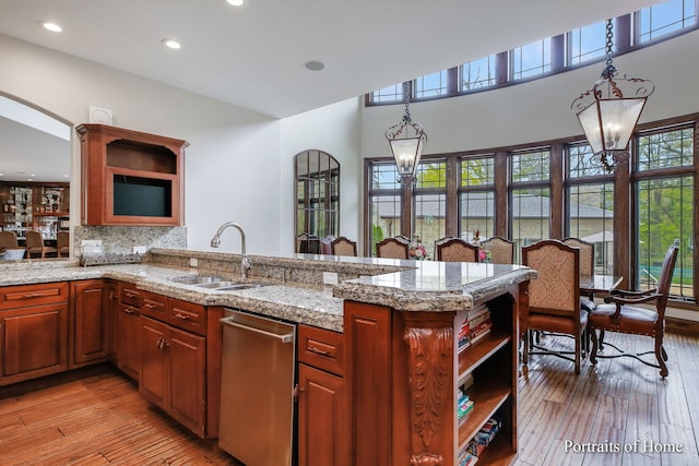 kitchen featuring sink, tasteful backsplash, kitchen peninsula, pendant lighting, and light hardwood / wood-style floors