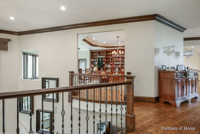 corridor with an inviting chandelier, hardwood / wood-style floors, and crown molding