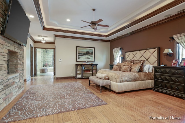 bedroom with crown molding, ceiling fan, a tray ceiling, and light hardwood / wood-style flooring