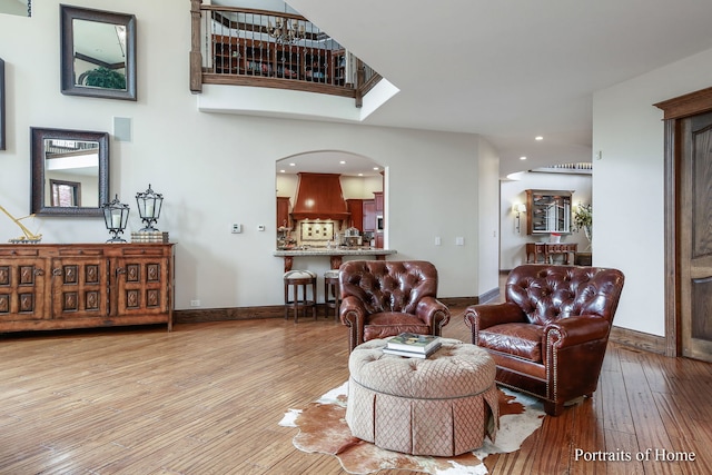 living room with a towering ceiling and light wood-type flooring