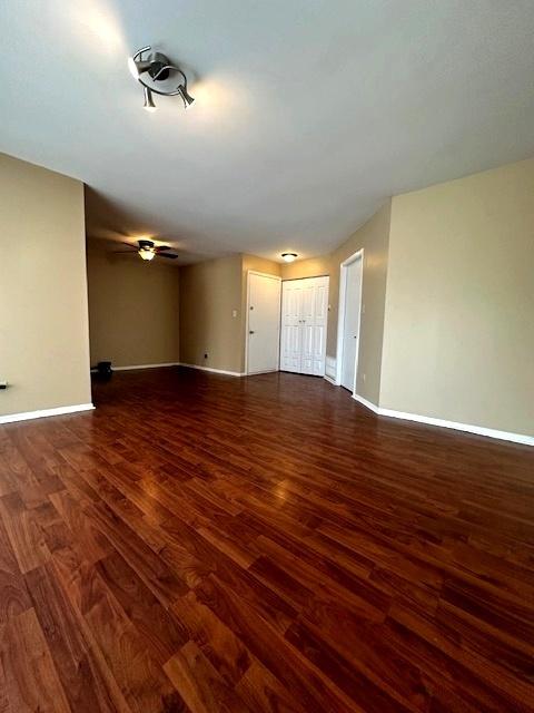 unfurnished living room with dark wood-type flooring and ceiling fan