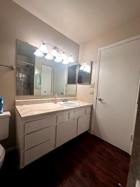 bathroom with hardwood / wood-style flooring, a shower, vanity, and toilet