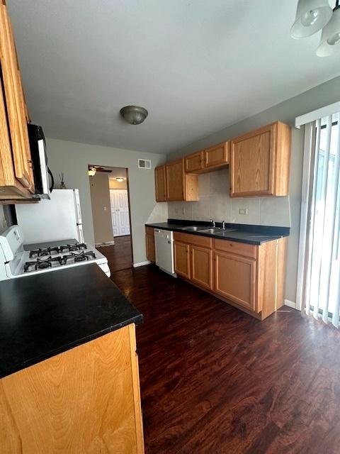 kitchen featuring tasteful backsplash, dishwasher, white gas range, sink, and dark hardwood / wood-style flooring