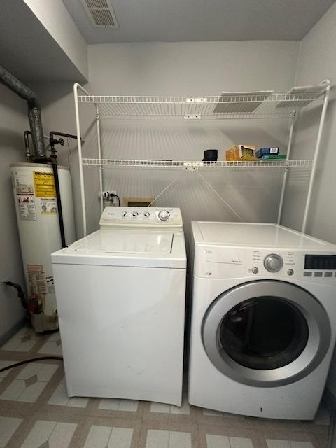 washroom with gas water heater and washer and clothes dryer