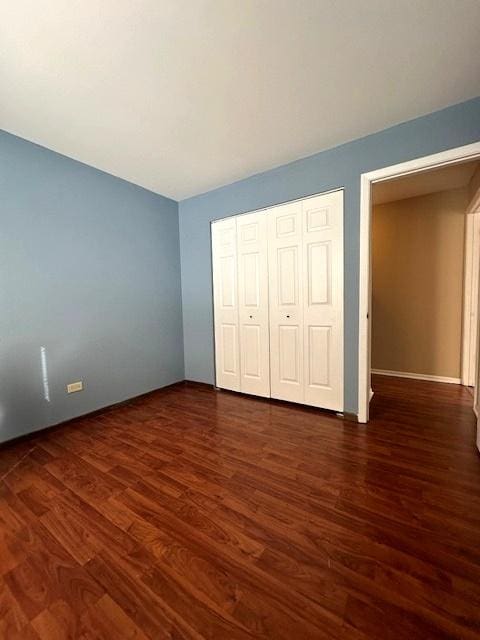 unfurnished bedroom with a closet and dark hardwood / wood-style floors