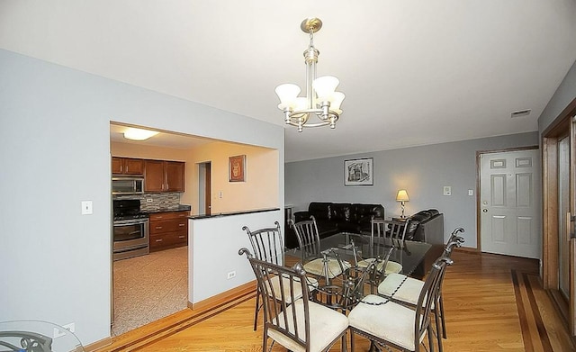 dining space featuring an inviting chandelier and light hardwood / wood-style flooring