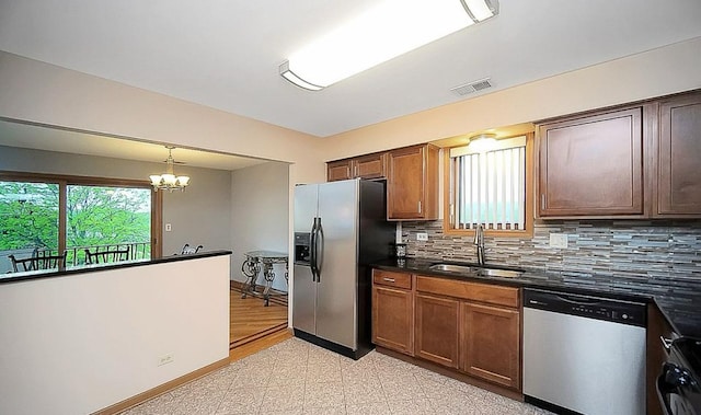 kitchen with sink, hanging light fixtures, a notable chandelier, stainless steel appliances, and backsplash