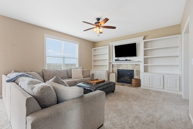 carpeted living room with a tiled fireplace and ceiling fan