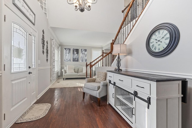 foyer featuring a towering ceiling, ornamental molding, dark hardwood / wood-style flooring, and a chandelier