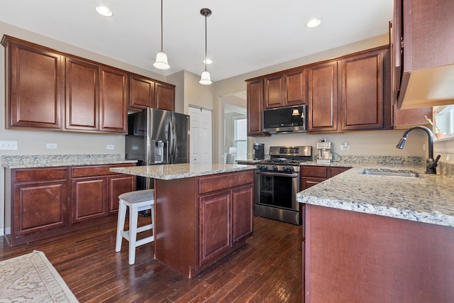 kitchen with sink, hanging light fixtures, stainless steel appliances, dark hardwood / wood-style floors, and a center island