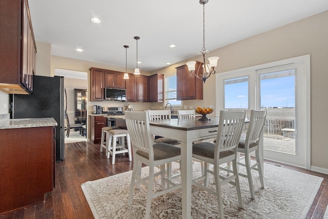 dining space with dark wood-type flooring, a chandelier, and sink