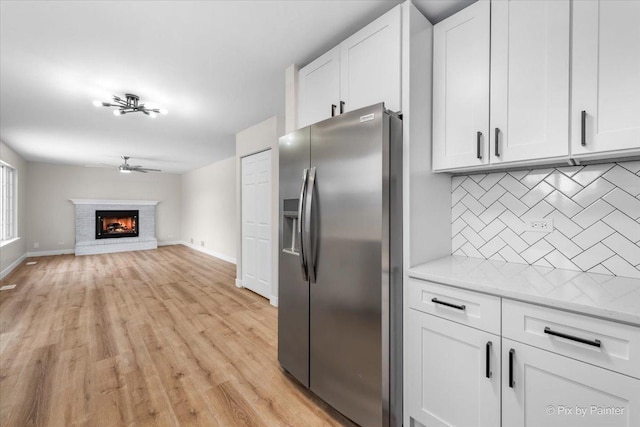 kitchen featuring light stone countertops, stainless steel fridge with ice dispenser, decorative backsplash, and white cabinets