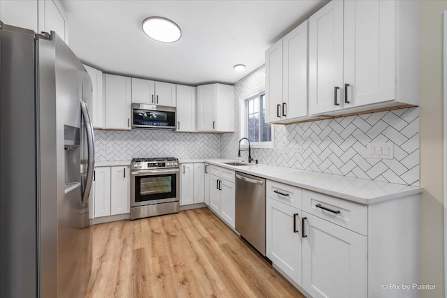 kitchen with stainless steel appliances, sink, and white cabinets