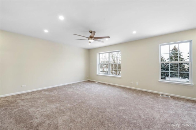 carpeted spare room featuring plenty of natural light and ceiling fan