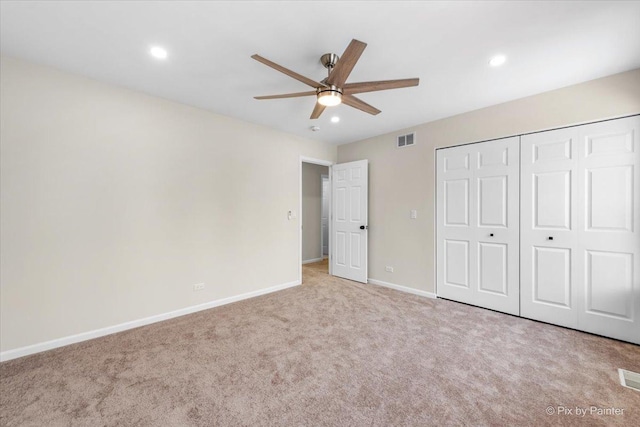 unfurnished bedroom featuring light carpet, a closet, and ceiling fan