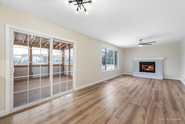 unfurnished living room with a brick fireplace, ceiling fan, and light hardwood / wood-style flooring