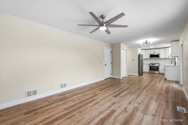 unfurnished living room with ceiling fan, sink, and light hardwood / wood-style floors