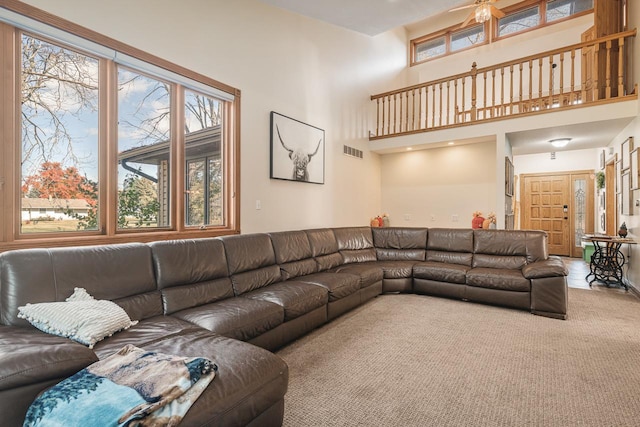 living room featuring carpet floors, ceiling fan, and a high ceiling