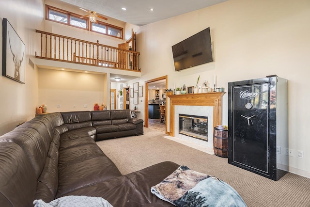 carpeted living room featuring a towering ceiling and a fireplace