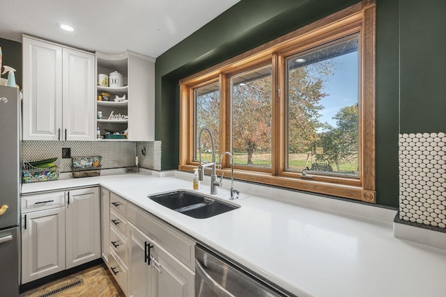 kitchen with stainless steel appliances, sink, white cabinets, and decorative backsplash