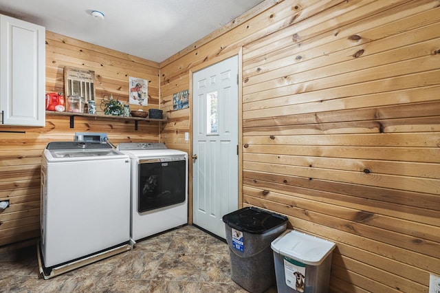 laundry area with cabinets, independent washer and dryer, and wood walls