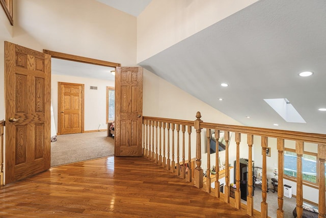 hall with dark wood-type flooring and lofted ceiling with skylight