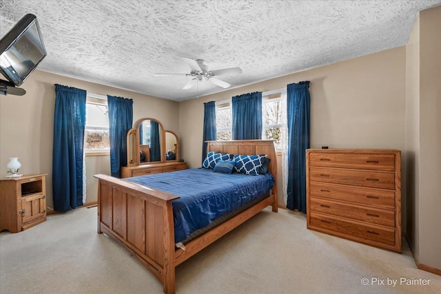 bedroom with ceiling fan, light colored carpet, multiple windows, and a textured ceiling