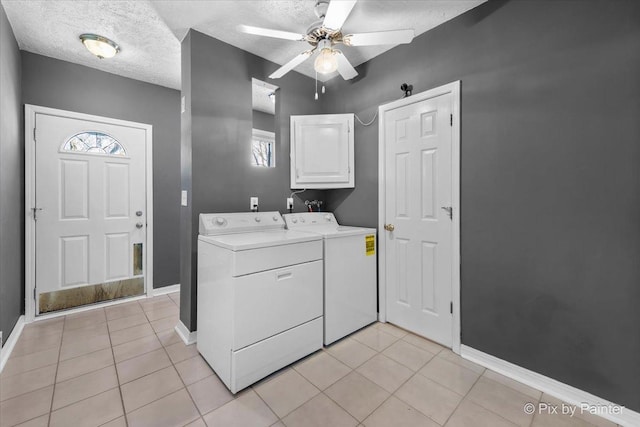 clothes washing area featuring cabinets, washing machine and dryer, a textured ceiling, and light tile patterned floors