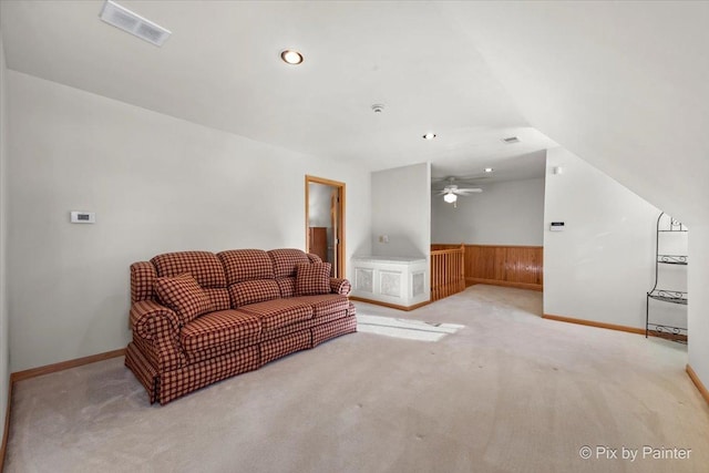 living room featuring light carpet, ceiling fan, and wood walls