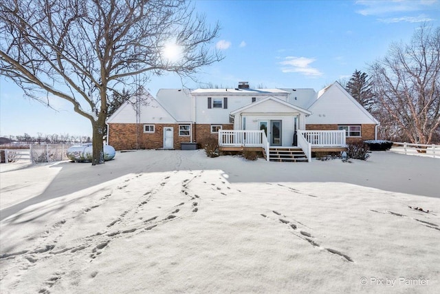 snow covered back of property with a wooden deck