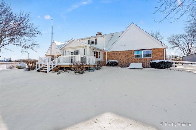 snow covered house featuring a wooden deck