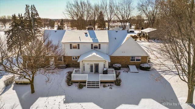 snow covered house featuring a wooden deck