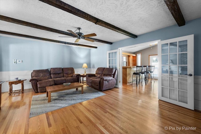 living room featuring lofted ceiling with beams, ceiling fan, a textured ceiling, and light hardwood / wood-style floors