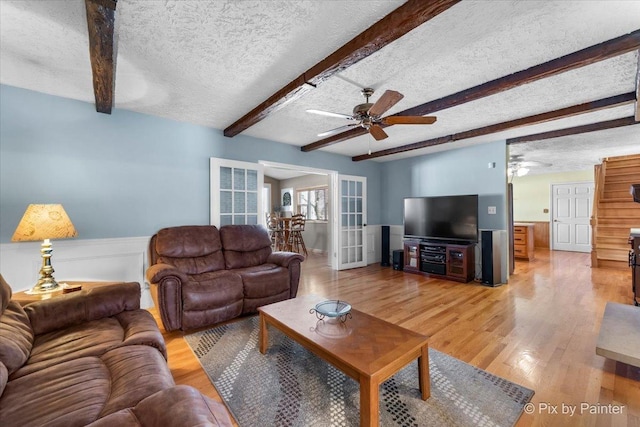 living room featuring beam ceiling, wood-type flooring, ceiling fan, and a textured ceiling