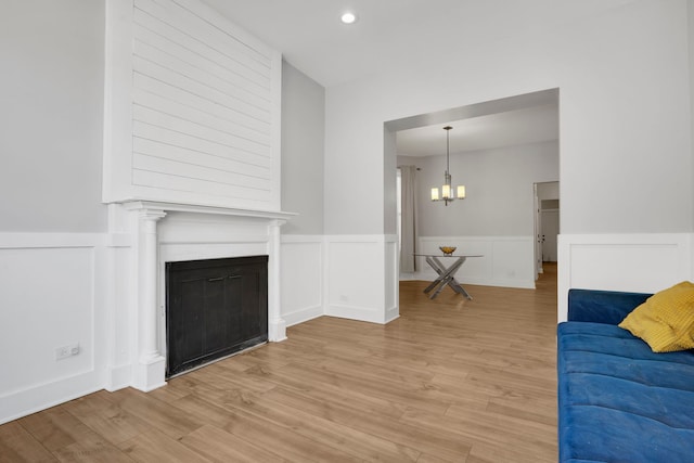 living room with light hardwood / wood-style flooring, a large fireplace, and a chandelier