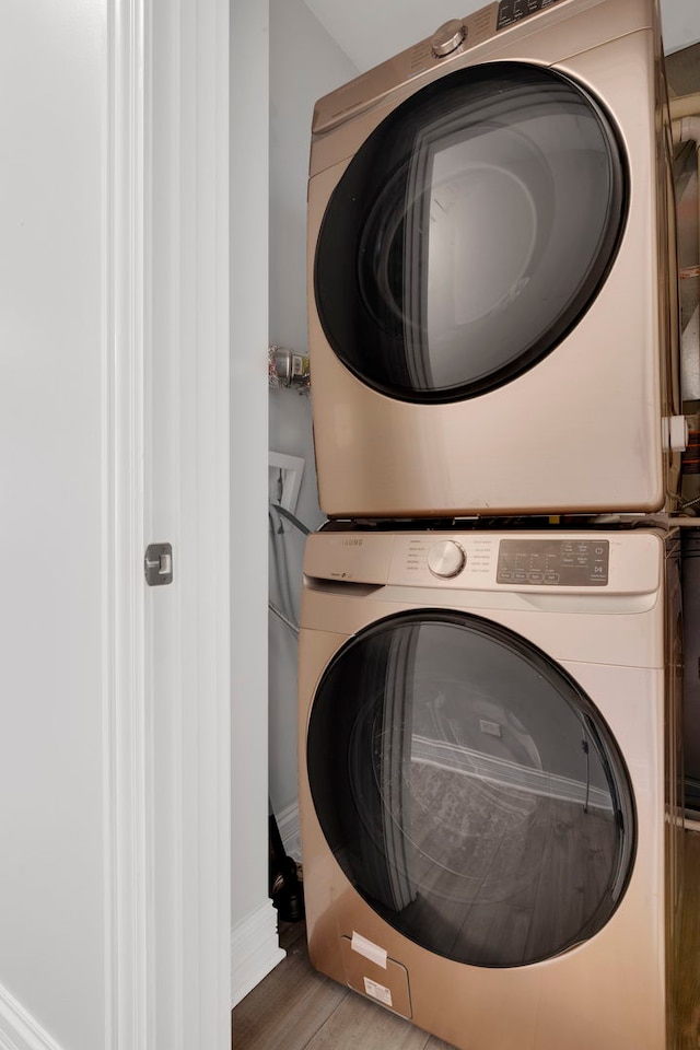 washroom featuring hardwood / wood-style flooring and stacked washer and dryer