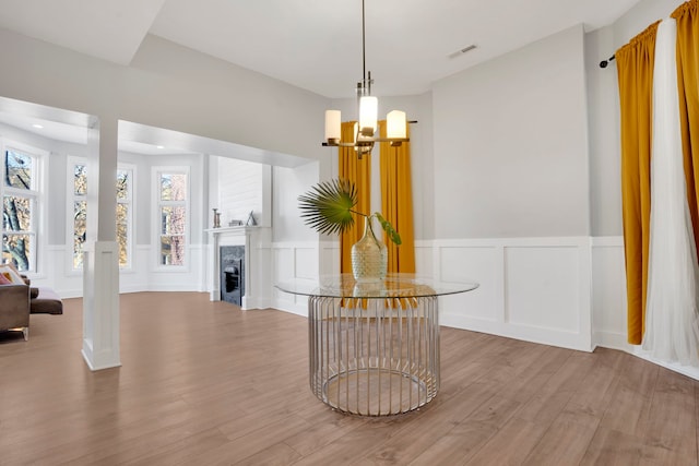 dining room featuring wood-type flooring, an inviting chandelier, and a high end fireplace