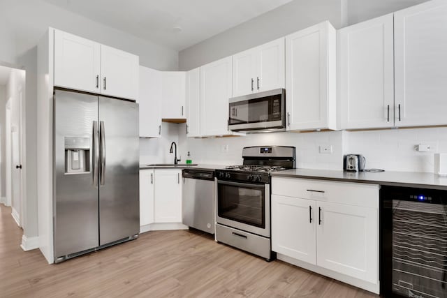 kitchen with wine cooler, sink, appliances with stainless steel finishes, decorative backsplash, and white cabinets