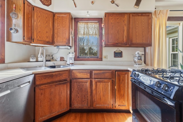 kitchen featuring stainless steel dishwasher, black range with gas cooktop, light hardwood / wood-style floors, and sink