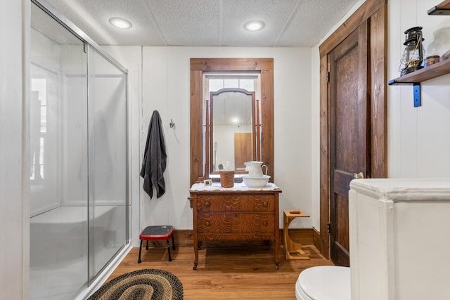 bathroom featuring wood-type flooring, toilet, and a shower with door