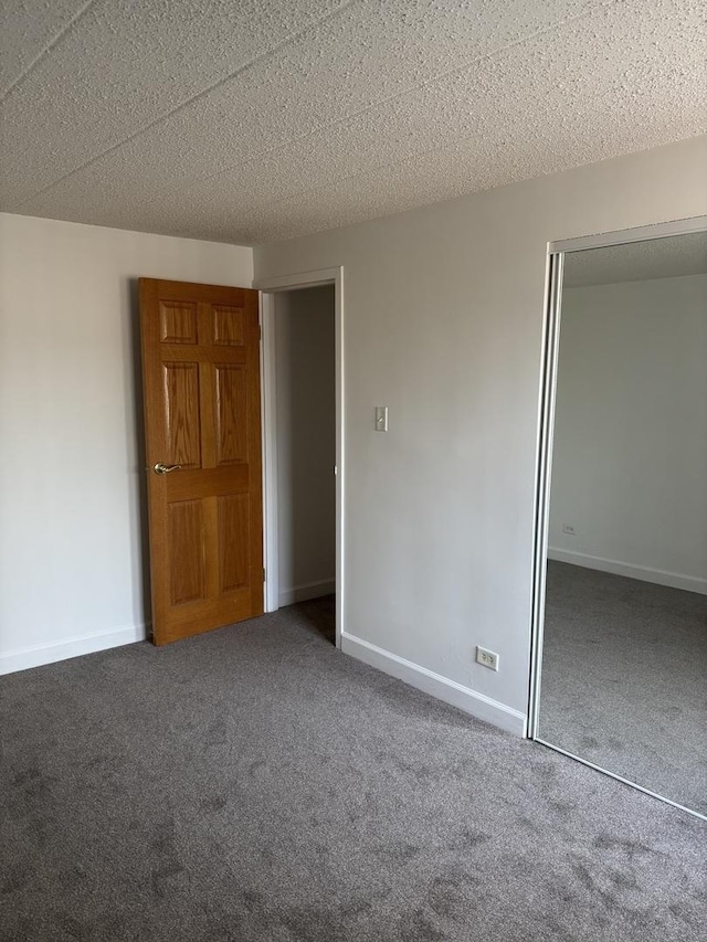 unfurnished bedroom with dark carpet, a closet, and a textured ceiling