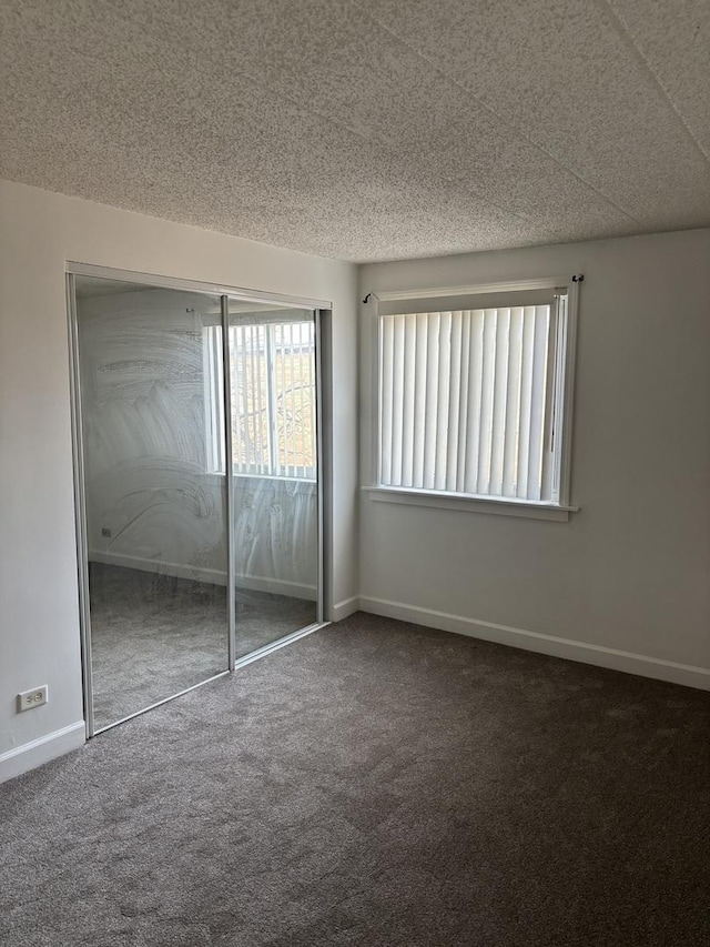 unfurnished bedroom featuring a closet and dark colored carpet