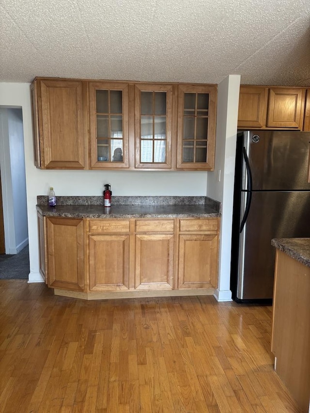 kitchen featuring a textured ceiling, stainless steel fridge, and light hardwood / wood-style floors